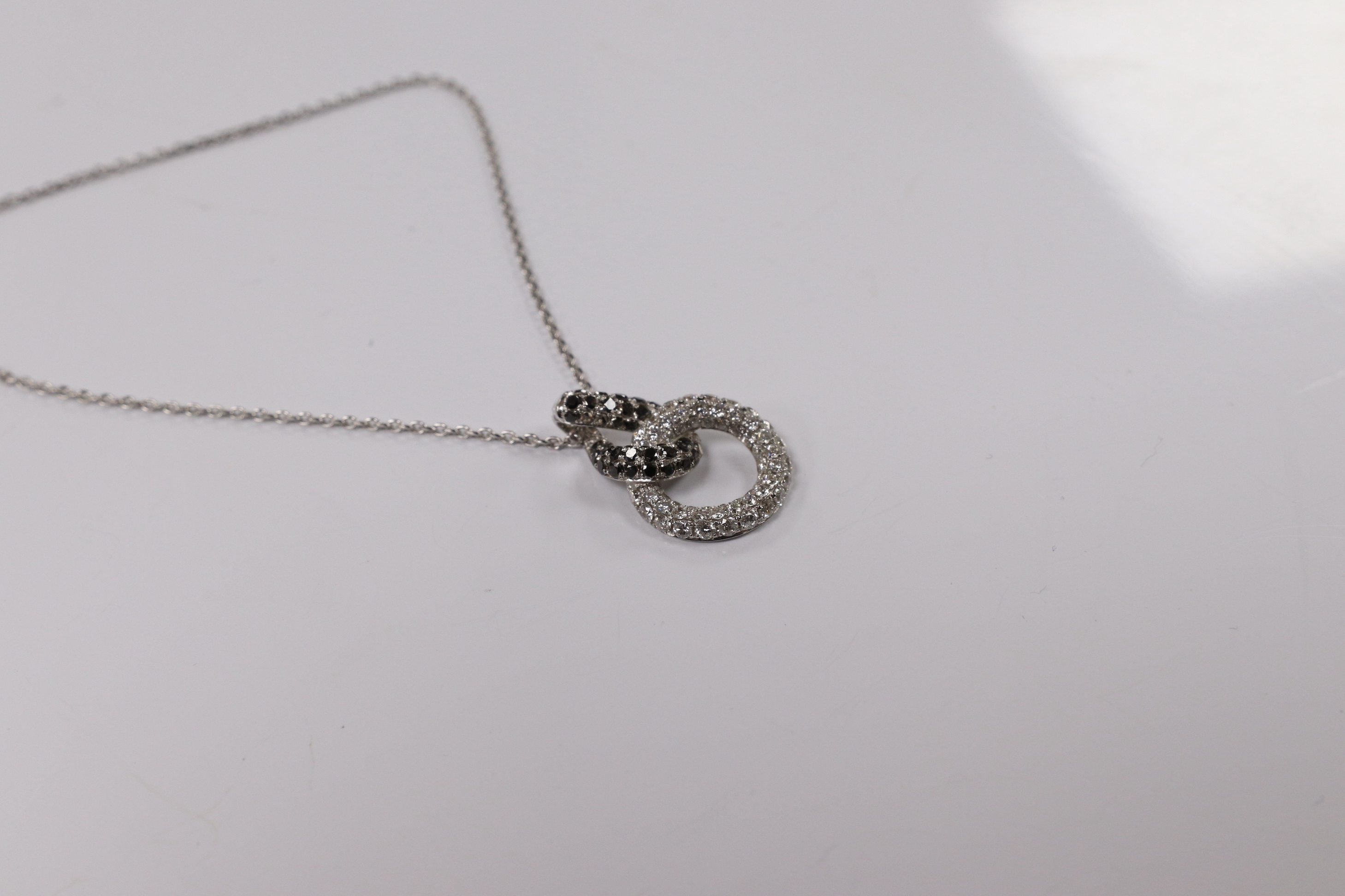 A modern 18k white metal and diamond chip set double loop pendant, 20mm, on an 18k white metal chain, 40cm, gross weight 4.1 grams. Condition - fair